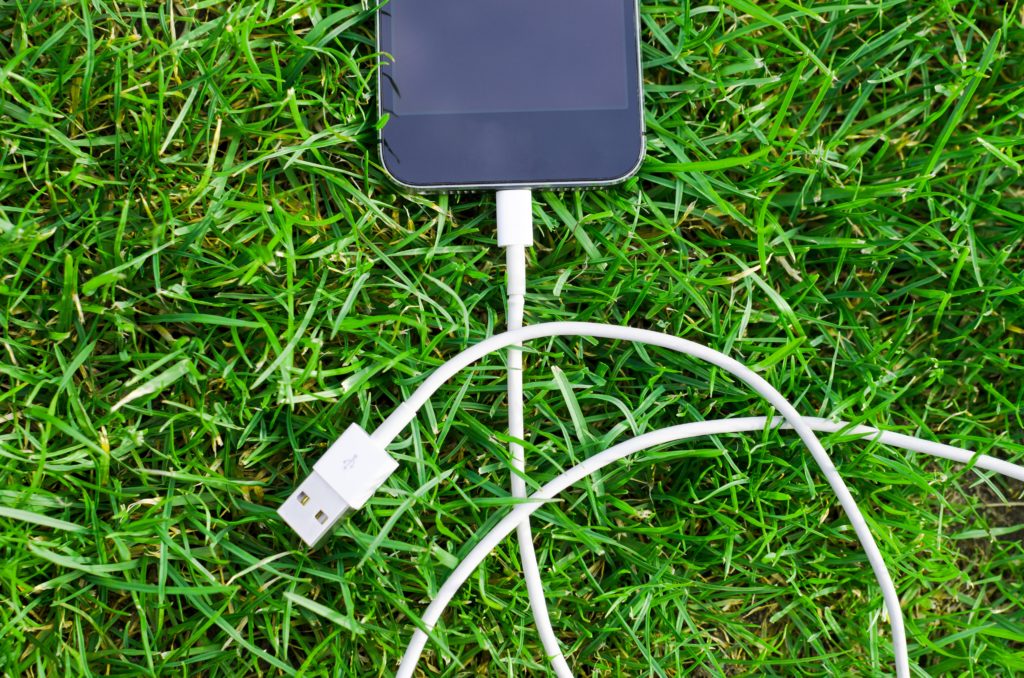 Smartphone e cavo per carica batteria sull'erba