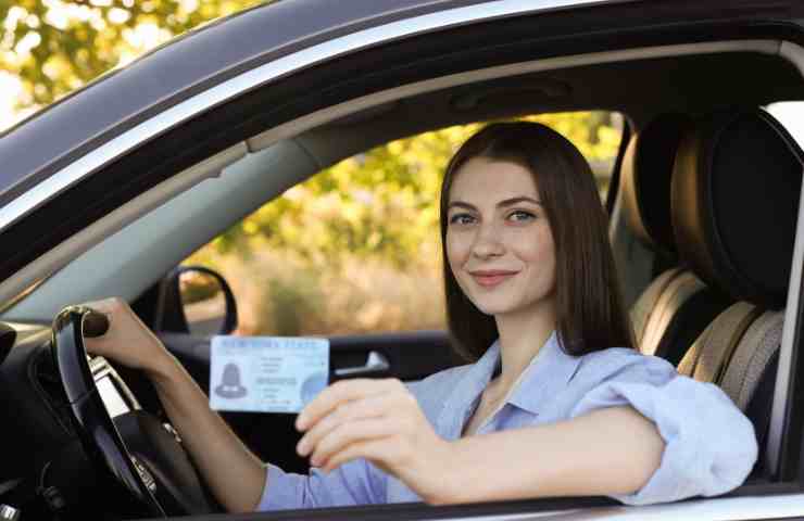 donna in auto con in mano patente